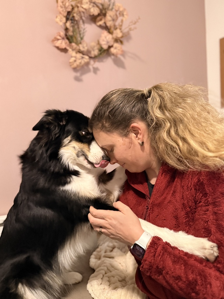 Ein Hund hält seinen Kopf an den von einer Frau und schleckt ihr über die Nase.