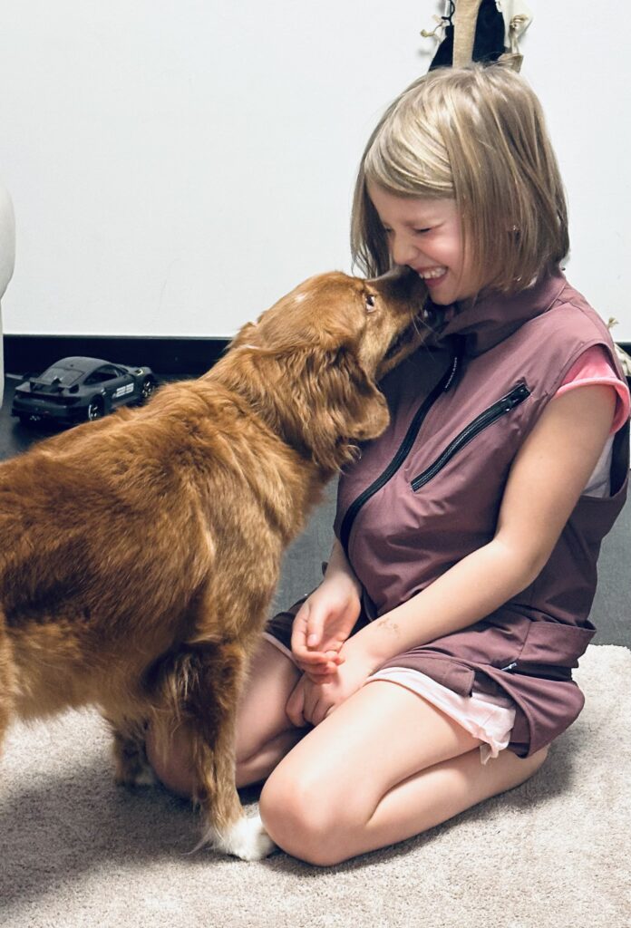 Ein Mädchen bekommt ein Bussi von einem Hund.